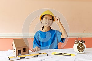 Asian girl has ambition to be a structural engineer with a helmet and the building plan put on the table.