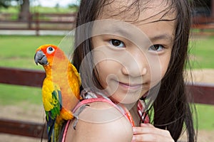 Asian girl has a parrot perched on her shoulder,child happy with the bird in the zoo