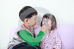 Asian girl having respiratory illness helped by brother with inhaler. Happy family concept.