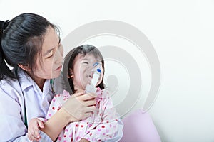 Asian girl having respiratory illness helped by health professional with inhaler.