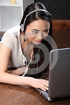 Asian girl with headphones using skype on laptop photo