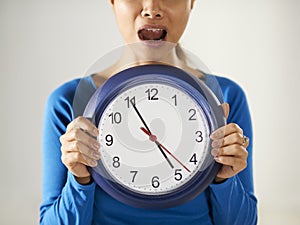 Asian girl holding big blue clock with stress