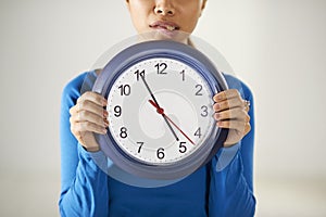 Asian girl holding big blue clock with stress