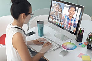 Asian girl holding computer for video call, with smiling diverse high school pupils on screen