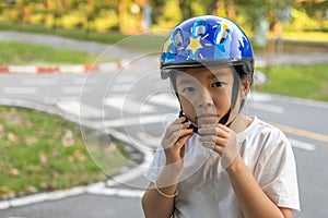 Asian girl learns to ride bike in park. Portrait of a cute kid on bicycle
