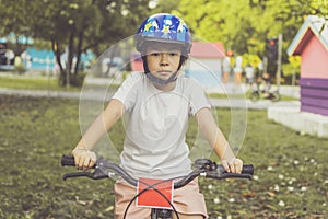 Asian girl learns to ride bike in park. Portrait of a cute kid on bicycle