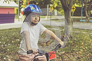 Asian girl learns to ride bike in park. Portrait of a cute kid on bicycle