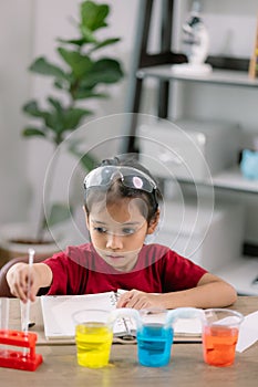 Asian girl making Walking Water experiment. Food color is added to the water in the glass, water moves along the paper, and then