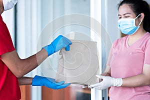 Asian girl with mask and safety gloves receiving food bag from delivery man