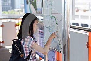 Asian girl orientating herself on the public transport map,Student looks at maps with public transport for travel in the big city
