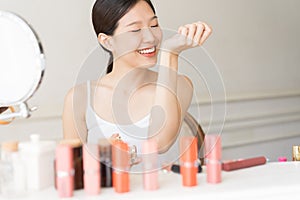 Asian girl with perfume, young woman applying perfume on her wrist and  smelling.