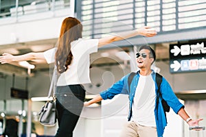 Asian girl picking up her boyfriend at airport`s arrival gate, welcomes back home from studying or working abroad