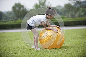 Asian girl play ball in the grass