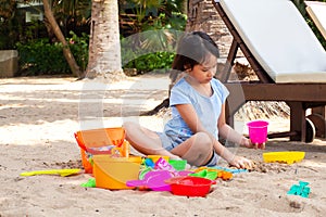 Asian girl playing sand with sand toys on beach