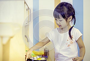 Asian girl playing toy kitchen