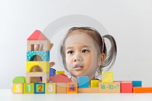 Asian girl playing wooden building blocks.