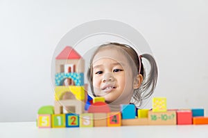 Asian girl playing wooden building blocks.