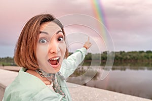 Asian girl poses against a huge bright rainbow after the rain. The concept of wonder and hope in life