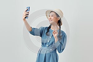 Asian girl posing isolated on white background, doing selfie shot on mobile phone spreading hands