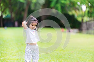 Asian girl pretends to throw an orange ball in her hand behind her head. Children play on the bright green lawn. Kids exercise.