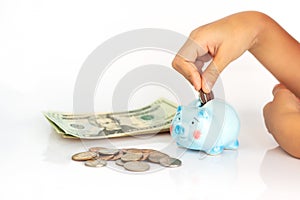 Asian girl putting dollar coin in piggy bank