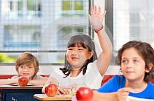 Asian girl raising hand in multi ethnic elementary classroom photo
