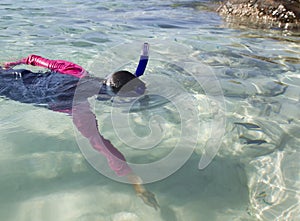 Asian girl reaches for fish while snorkeling