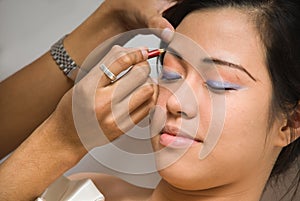 Asian girl receiving eye-liner make-up