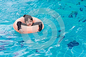 Asian girl with rubber ring in swimming pool