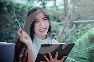 Asian girl`s business style hold a pen and smiling emotion positive thing of the day