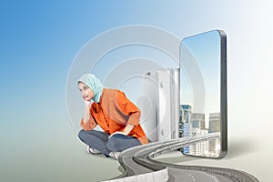 Asian girl in a scarf sitting with a suitcase with a city view on the mobile phone screen