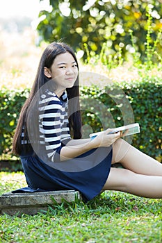 asian girl and school book in hand toothy smiling face with happiness emotion in green park