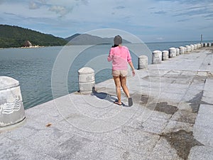 asian girl in shorts walking by the pier on sunny afternoon
