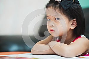 Asian girl show displeasure and strongly resist doing homework. Child sat with arms crossed and glanced thoughtfully.