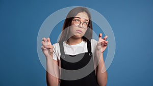 Asian girl showing with hands and two fingers like quotes gesture, bend fingers isolated over blue