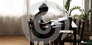 Asian girl sitting at desk in living room in living room on laptop doing work notes young woman concentrate on writing on laptop