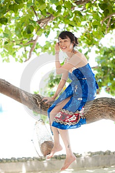 Asian girl sitting on tree trunk
