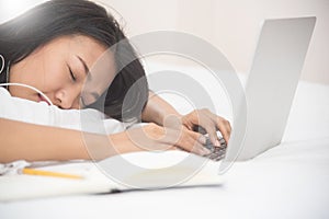 Asian girl sleeping with laptop on her bed.