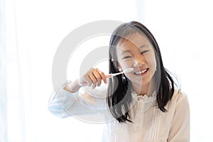 Asian girl smiles and holds a toothbrush on white background,healthy teeth concep