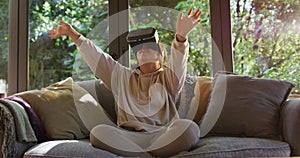 Asian girl smiling and gesturing while wearing vr headset sitting on the couch at home