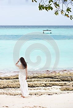 Asian girl standing on beach watching towards