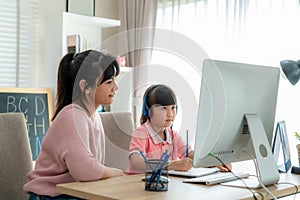 Asian girl student with mother video conference e-learning with teacher on computer in living room at home. Homeschooling and