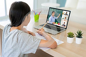 Asian girl student video conference e-learning with teacher and classmates on computer in living room at home. Homeschooling and