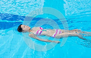An Asian girl is swimming backstroke in the swimmi photo