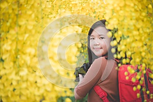 Asian girl take photo with blooming yellow flower