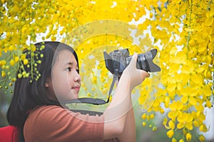 Asian girl take photo with blooming yellow flower