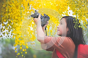 Asian girl take photo with blooming yellow flower