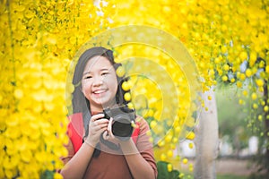 Asian girl take photo with blooming yellow flower