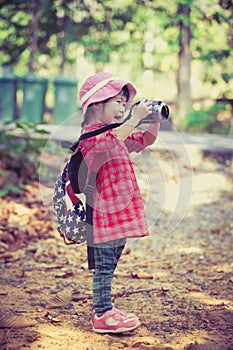 Asian girl taking photos by digital camera in garden. Vintage pi