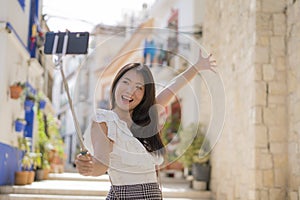 Asian girl taking self portrait on the street - young happy and attractive Asian Chinese woman visiting Seville in Spain taking